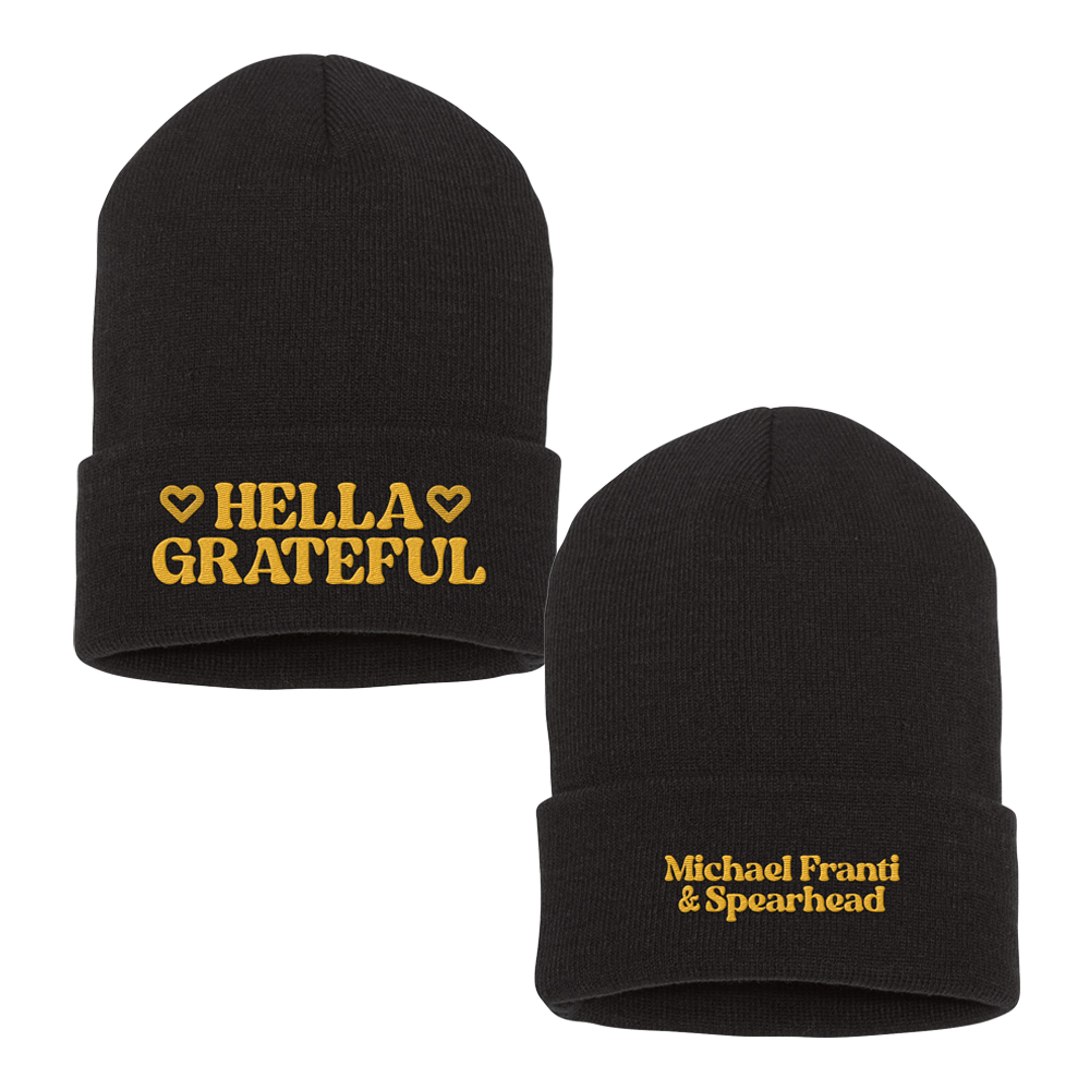 Black knit beanie hat with yellow embroidered text.