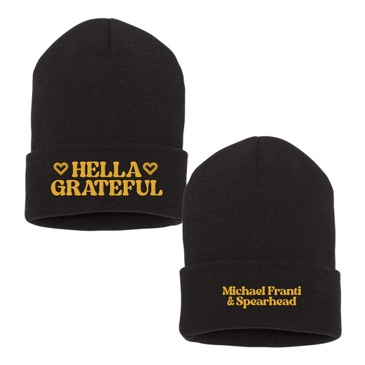 Black knit beanie hat with yellow embroidered text.