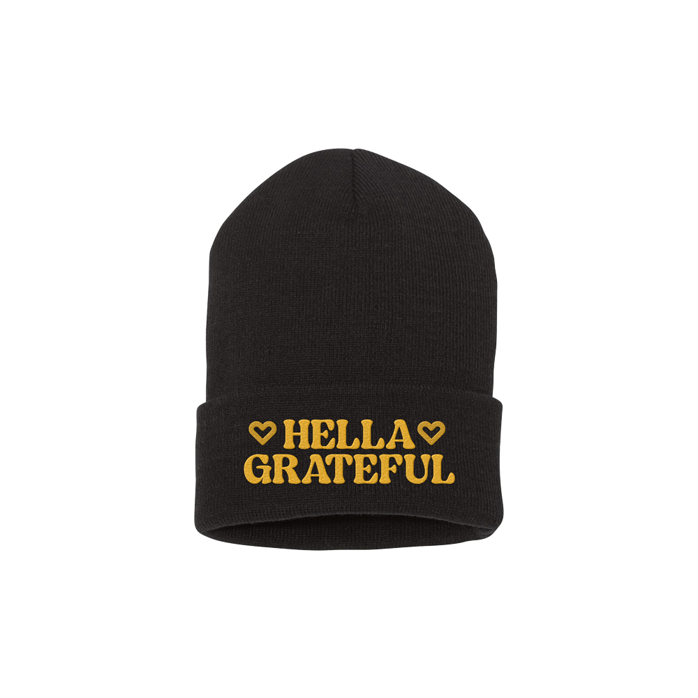 Black knit beanie with ’HELLA GRATEFUL’ embroidered in gold lettering.