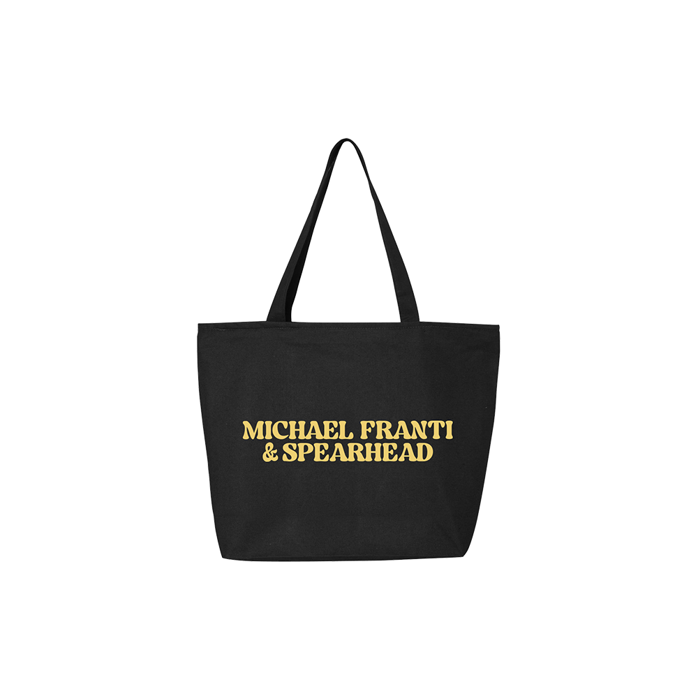 Black tote bag with ’MICHAEL FRANTI & SPEARHEAD’ printed in gold lettering.