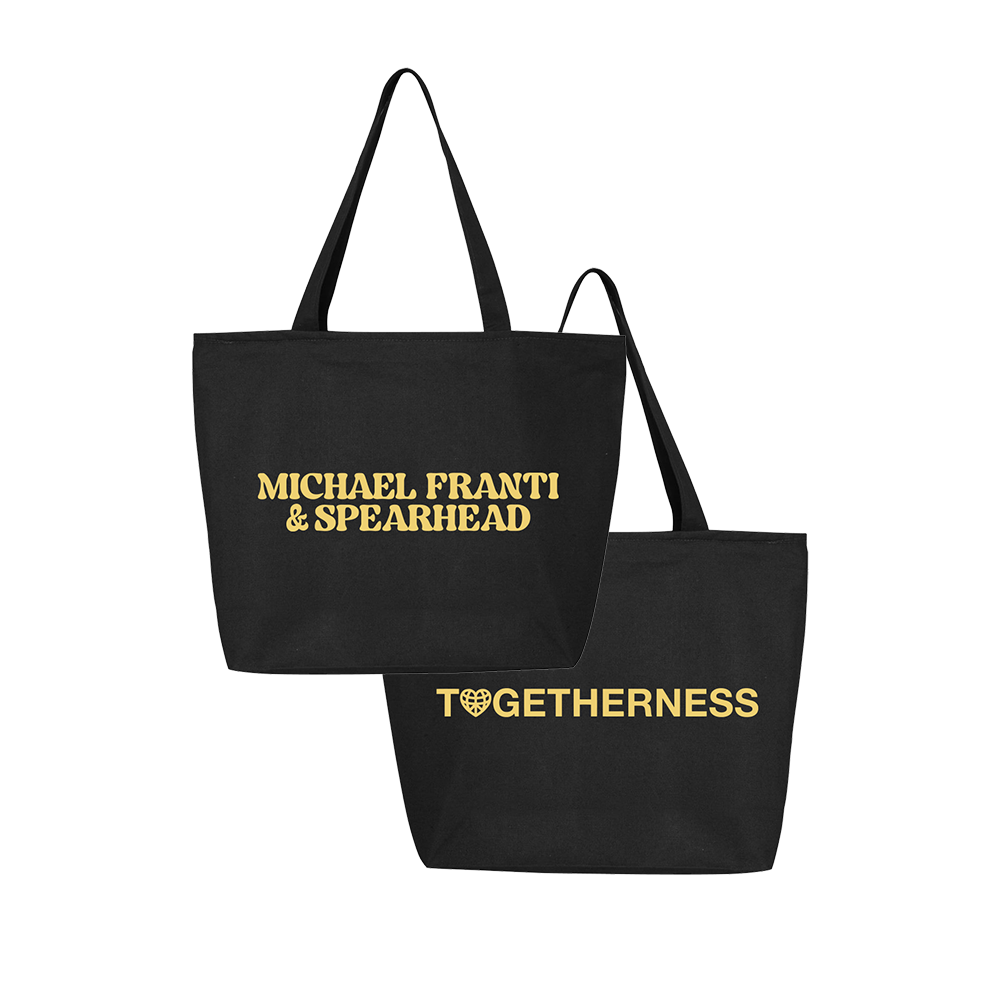 Black tote bag with gold text featuring ’Michael Franti & Spearhead’ on one side and ’Togetherness’ on the other.