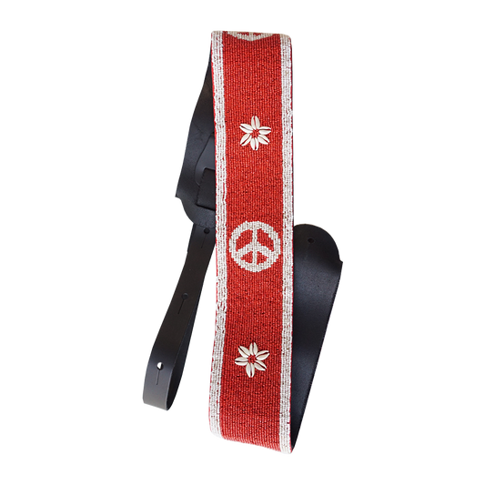 Red guitar strap with white peace symbol and flower designs.