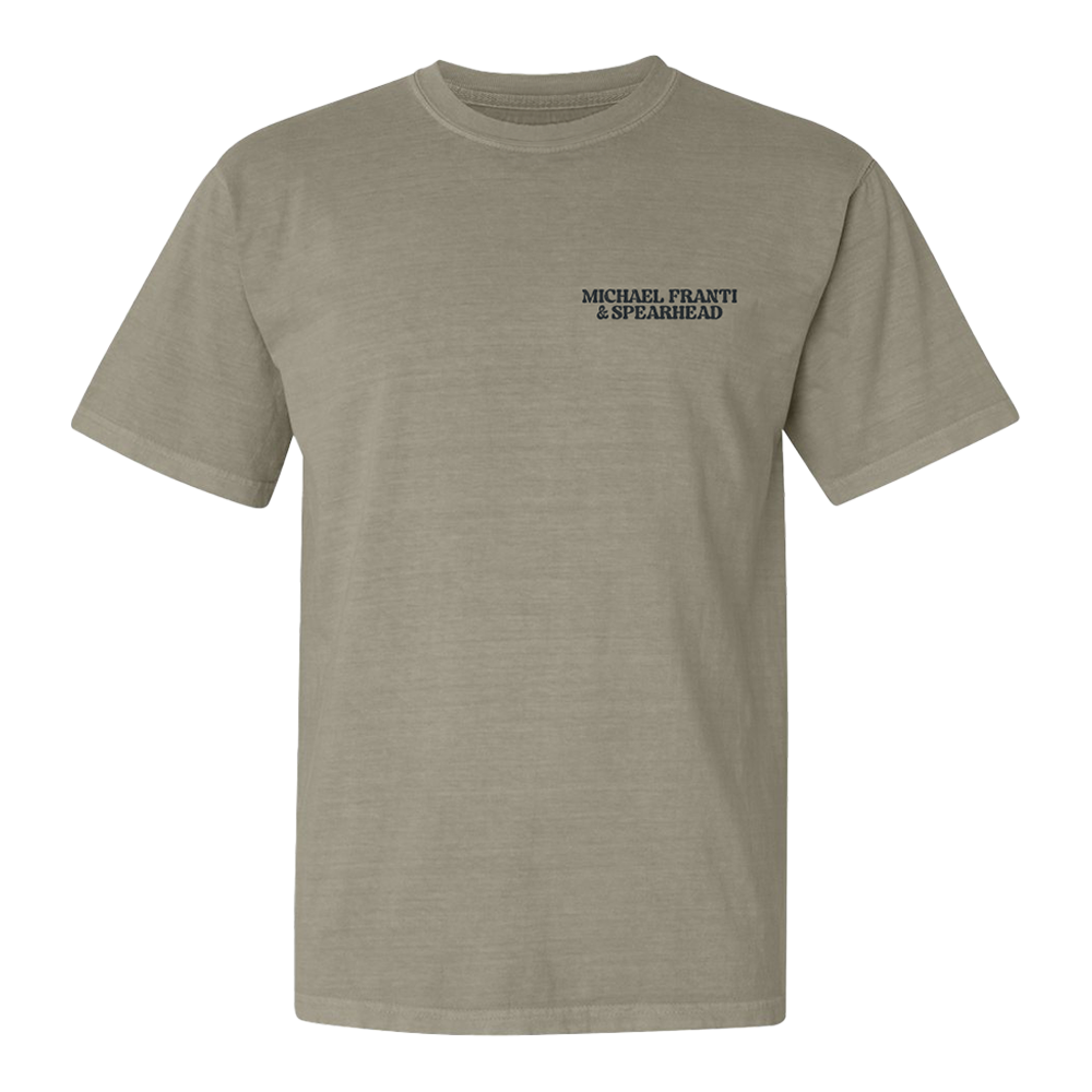 Khaki-colored t-shirt with ’MICHAEL FRANTI & SPEARHEAD’ printed on the chest.